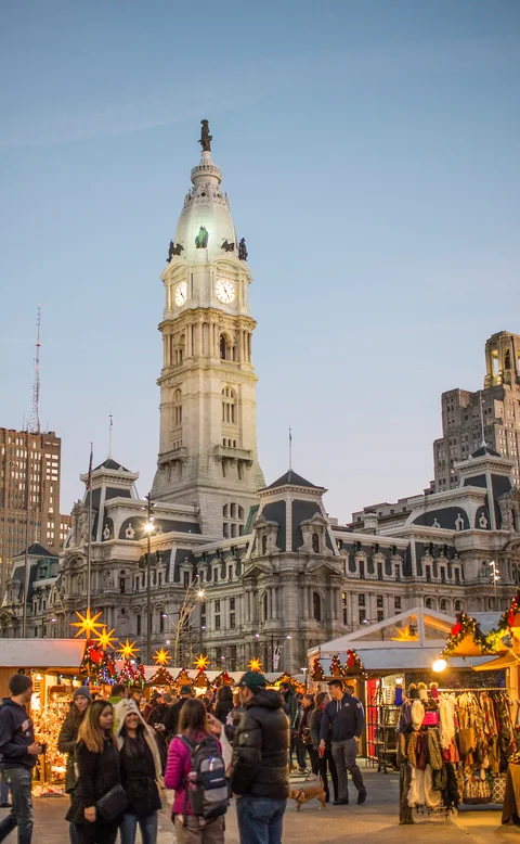 Barracas e visitantes do Christmas Village com a prefeitura da Filadélfia ao fundo. Fotografia de arquivo de 2017; mostra uma decoração de uma edição anterior.