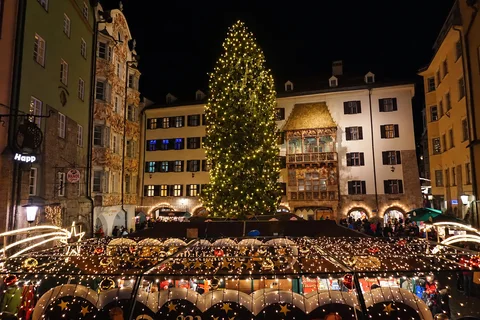 KI-generierte repräsentative Illustration. Fotovorlage: Weihnachtsbaum, Goldenes Dachl und Marktstände in Innsbruck bei Nacht. Aufgenommen 2016; dieses Archivfoto zeigt nicht die Gestaltung von 2026.