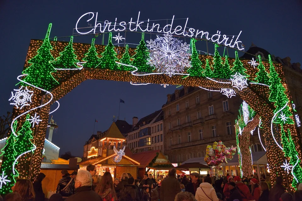 Beleuchtetes Eingangstor des Christkindelsmärik über Ständen und Besuchern am Place Broglie in Straßburg. Archivaufnahme aus der Weihnachtszeit 2013; sie zeigt eine frühere Szene, nicht die Gestaltung von 2026.