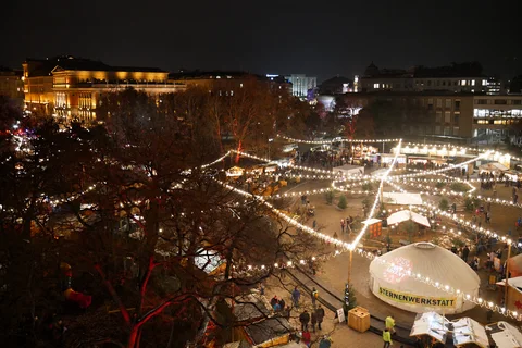 KI-generierte repräsentative Illustration. Fotovorlage: Nächtlicher Blick von oben auf Lichter und weiße Jurte am Karlsplatzmarkt. Aufgenommen 2018; dieses Archivfoto zeigt nicht die Gestaltung von 2026.