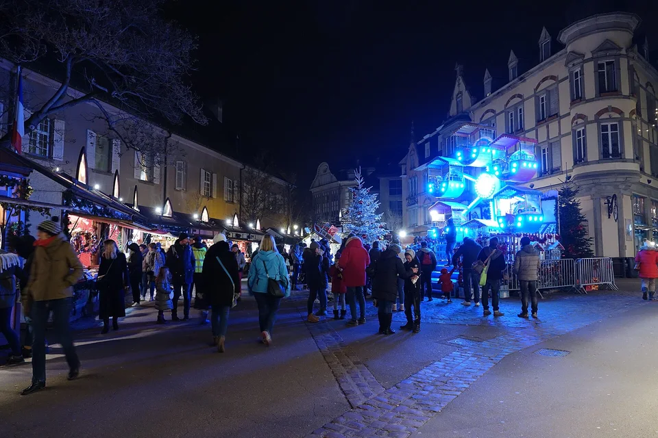 Weihnachtsmarktstände und beleuchtetes Karussell auf der Place des Martyrs-de-la-Résistance in Colmar. Archivfoto von 2018 zur Orientierung in der Umgebung und ihrer Architektur.
