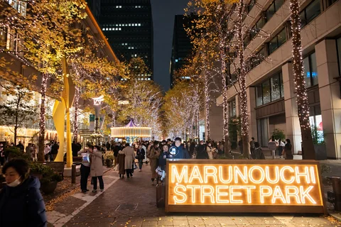 KI-generierte repräsentative Illustration. Fotovorlage: Beleuchtete Bäume und ein Schild von Marunouchi Street Park in Tokio bei Nacht. Archivfoto von 2022 einer früheren Gestaltung in Marunouchi im Zentrum von Tokio.