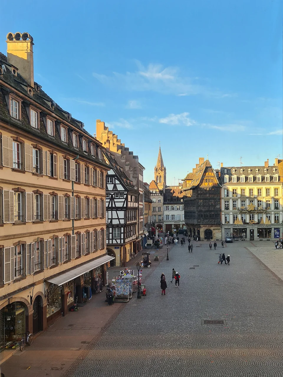 Erhöhter Blick auf das Kopfsteinpflaster des Place de la Cathédrale, Fachwerkfassaden und die Touristeninformation in Straßburg. Archivaufnahme des Ortes aus 2022; sie dokumentiert nicht den Weihnachtsmarkt von 2026.