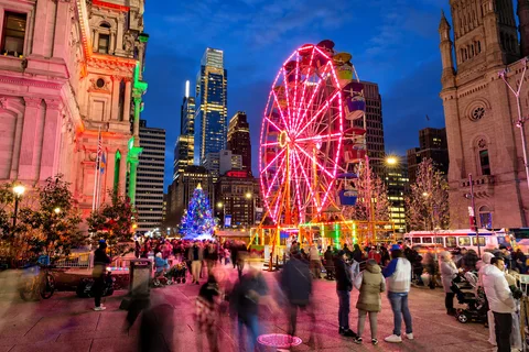 KI-generierte repräsentative Illustration. Fotovorlage: Beleuchtetes Riesenrad und Besucher im Christmas Village in Philadelphia bei Nacht. Archivfoto; das Aufnahmejahr ist nicht bestätigt.