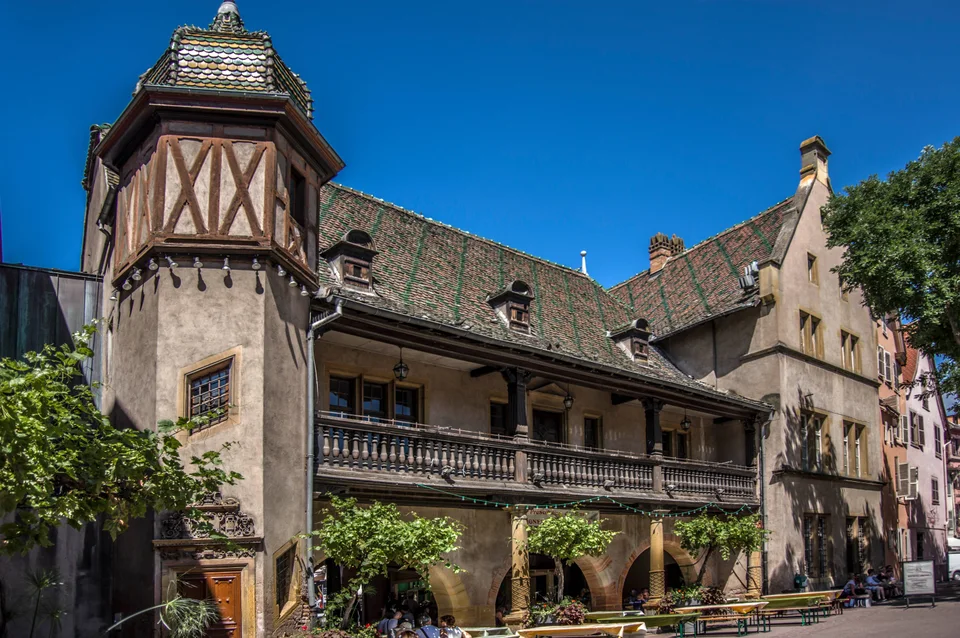Ziegeldach, Fachwerktürmchen und Balkon des Koïfhus vom Place de l’Ancienne Douane in Colmar aus gesehen. Aufnahme des Veranstaltungsorts aus 2016 außerhalb der Weihnachtszeit; sie zeigt nicht den Markt von 2026.