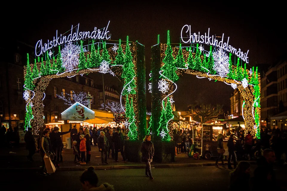 Beleuchteter Eingang des Christkindelsmärik und Holzhütten in Straßburg bei Nacht. Archivfoto von 2014; zu sehen ist eine frühere Gestaltung.
