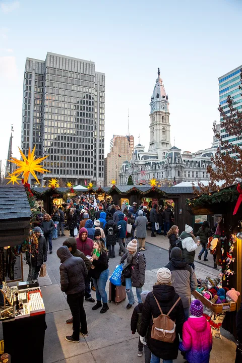 Stände und Besucher des Christmas Village im LOVE Park mit Philadelphias Rathaus im Hintergrund. Archivfoto; die Standanordnung 2026 kann abweichen.