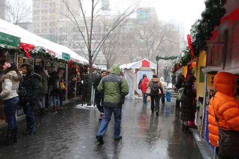 Schnee zwischen rot-weißen Ständen des Weihnachtsmarkts am Union Square in New York. Historische Aufnahme vom Dezember 2013; kein Nachweis für Gestaltung oder Wetter 2026.